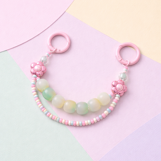 Pastel beaded keychain with pink flowers on a colorful geometric background