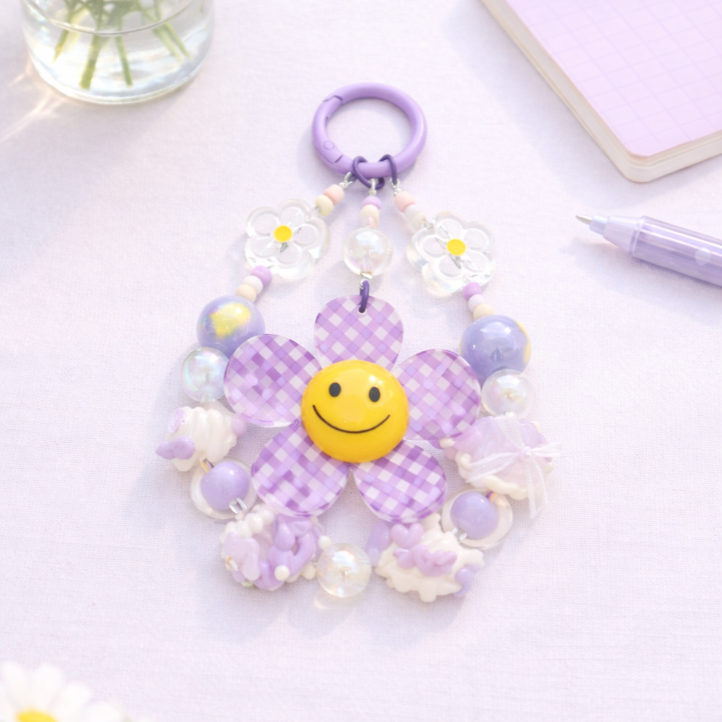 Purple flower-shaped keychain with a smiley face on a light purple background