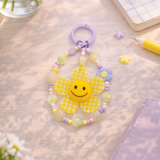 Children's toy with a smiley face on a light wooden surface with flowers and a notebook.