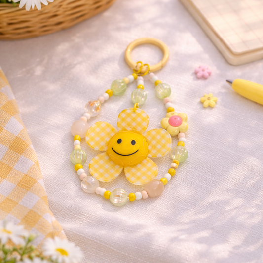 Yellow sun-shaped keychain with beads on a light surface with flowers and a basket.