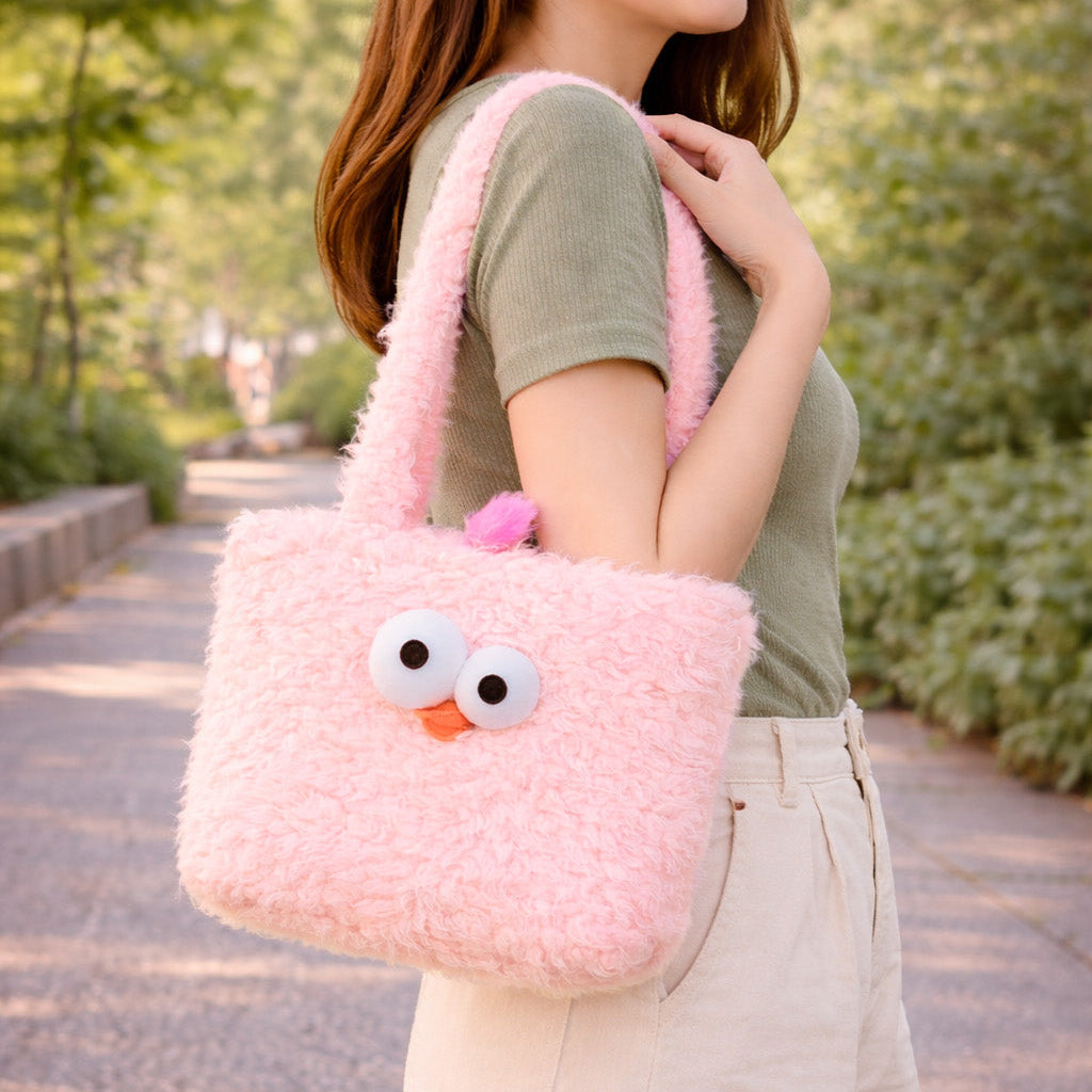 Person holding a pink fluffy bag with a face design outdoors.