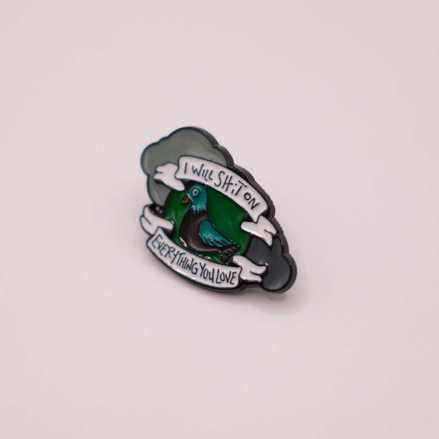 Enamel pin with a green bird design and text on a light gray background