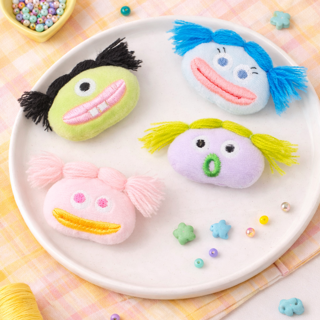 Three colorful face-shaped brroches on a plate with decorative elements on a checkered tablecloth.
