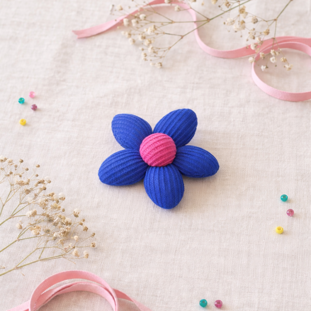 Blue and pink flower-shaped object on a textured surface with ribbons and small flowers.