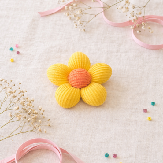 Yellow flower-shaped object with pink center on a light background with ribbons and flowers.