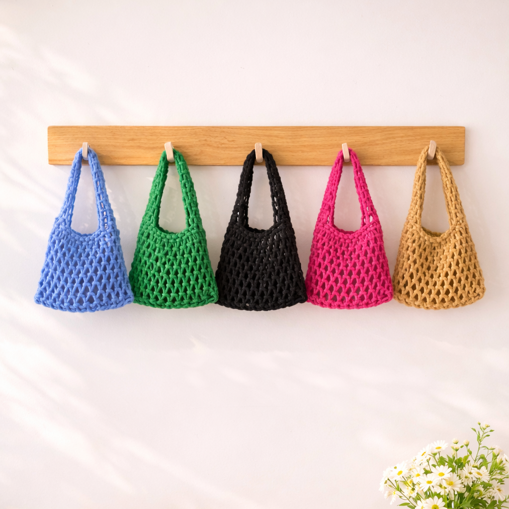 Colorful bags hanging on a wooden rack above a table with a hat, lemons, and a vase.