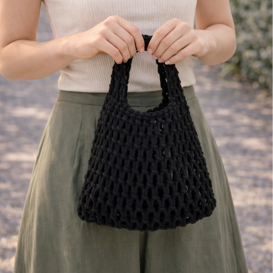 Woman holding a black woven handbag outdoors