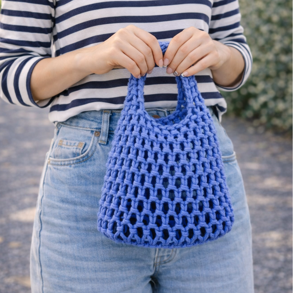 Person holding a blue crochet bag outdoors